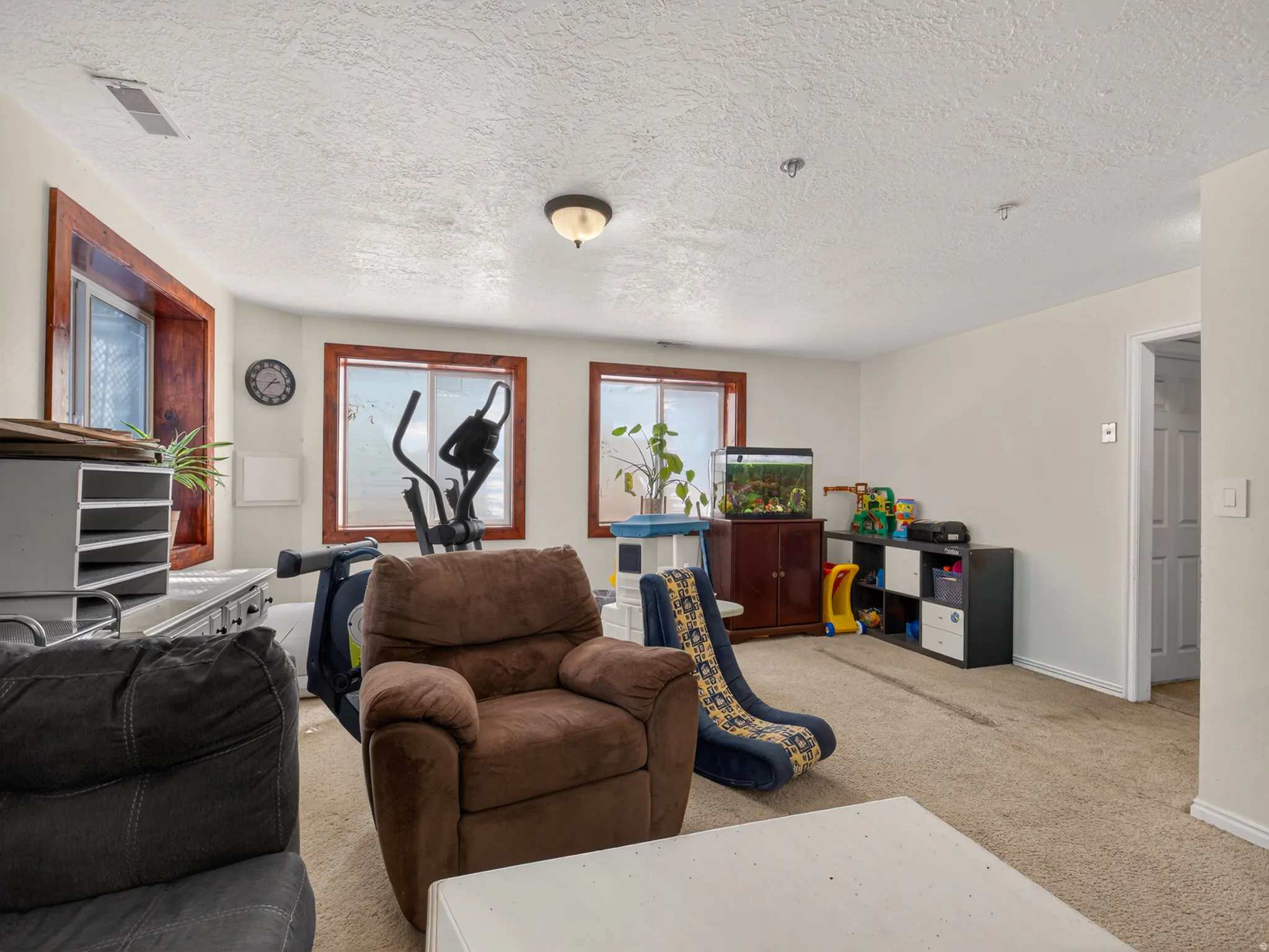 Basement family room with multiple windows featuring wood-finish trim