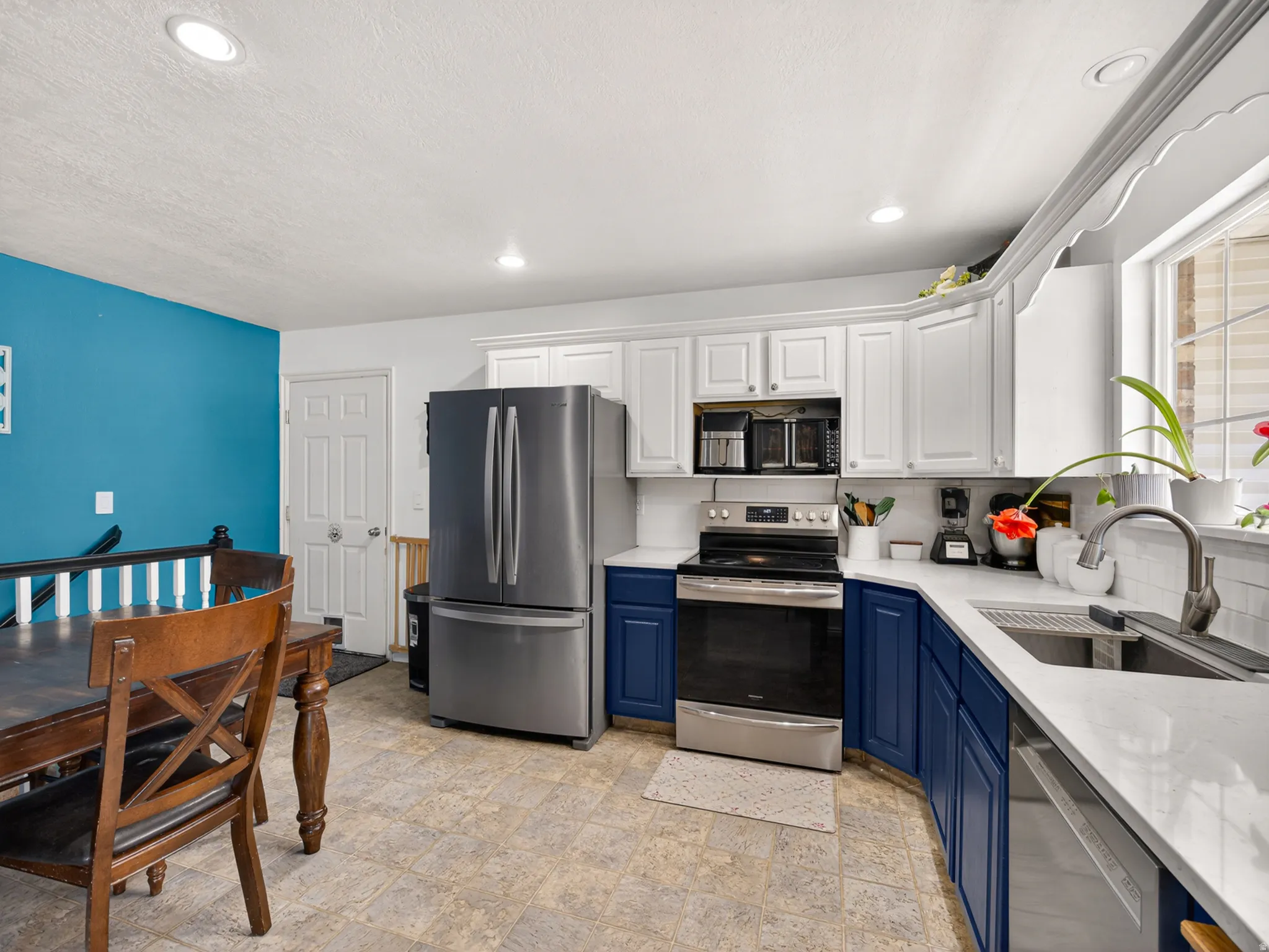 Modern kitchen featuring two-tone cabinetry, stainless steel appliances, recessed lighting, and light-toned countertops