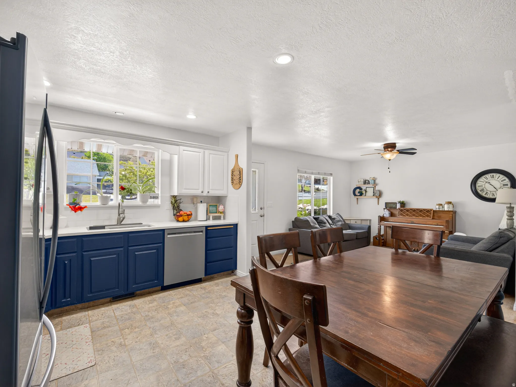 Open-concept living area featuring a kitchen with two-toned cabinetry, stainless steel appliances, and a white subway tile backsplash