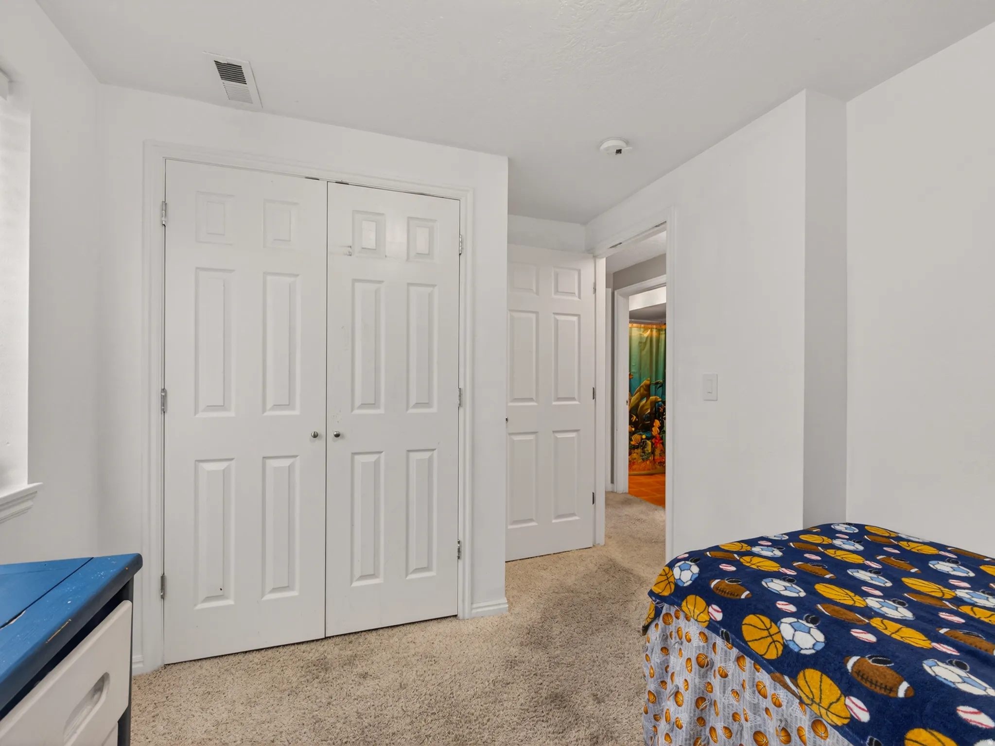 Secondary basement bedroom featuring white walls, and a pair of white paneled closet doors