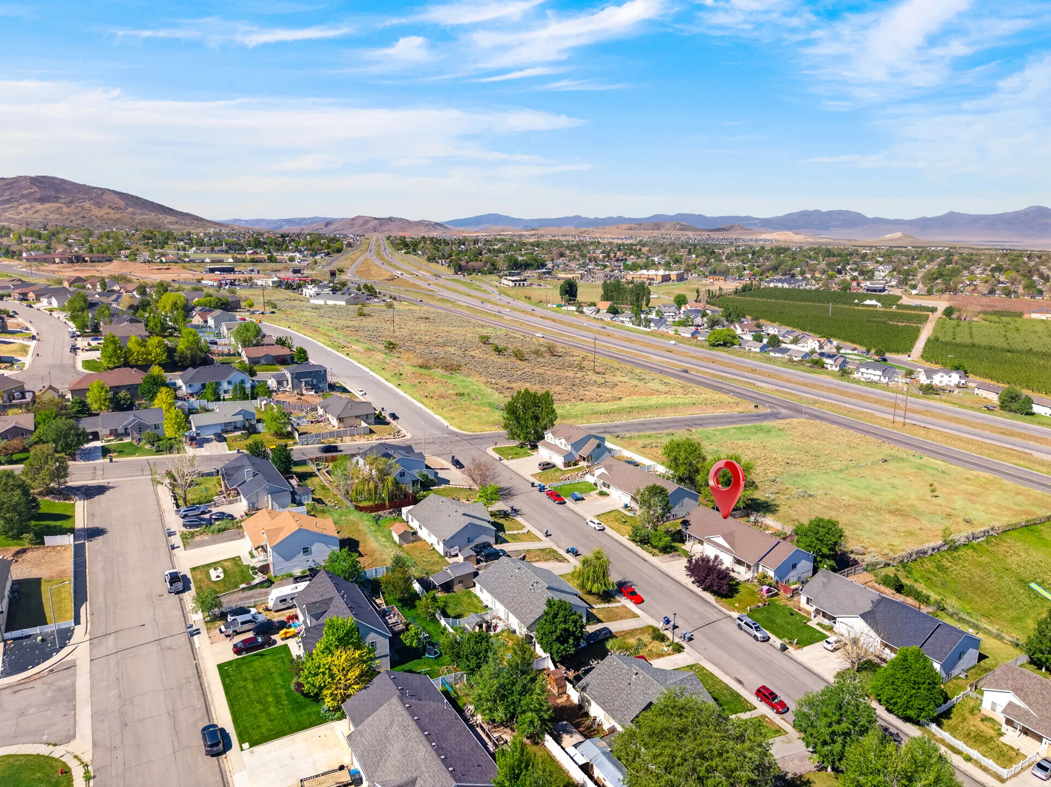 Aerial perspective showcasing a residential neighborhood with surrounding open land and distant mountains