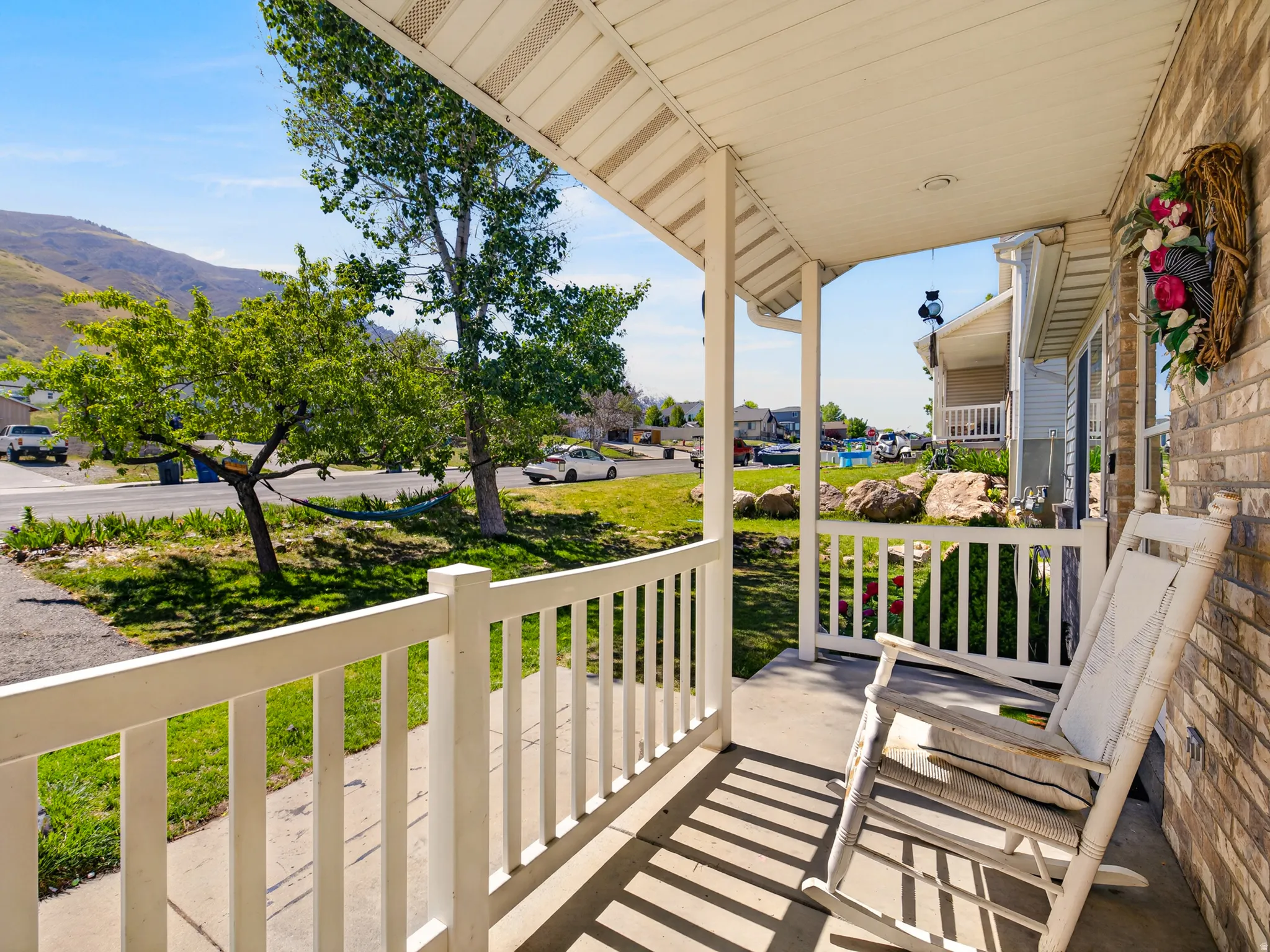 Inviting covered front porch with white railings and a brick exterior
