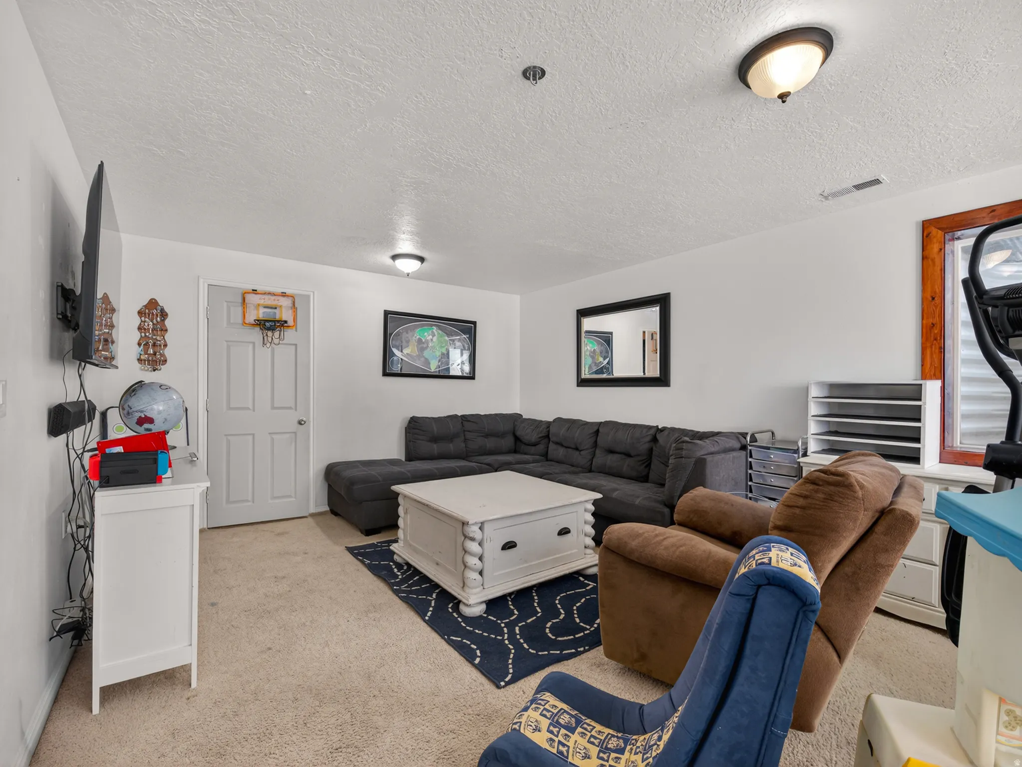 Basement family room featuring white walls, a white paneled door, and two flush-mount ceiling lights