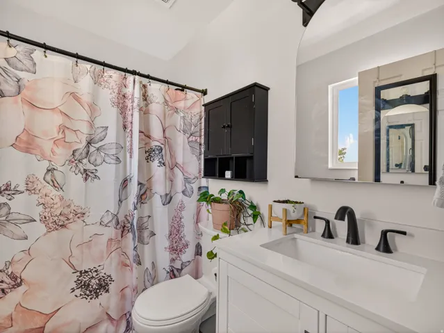 Primary bathroom featuring a white vanity with an integrated rectangular sink, matte black faucet, and a wall-mounted mirror