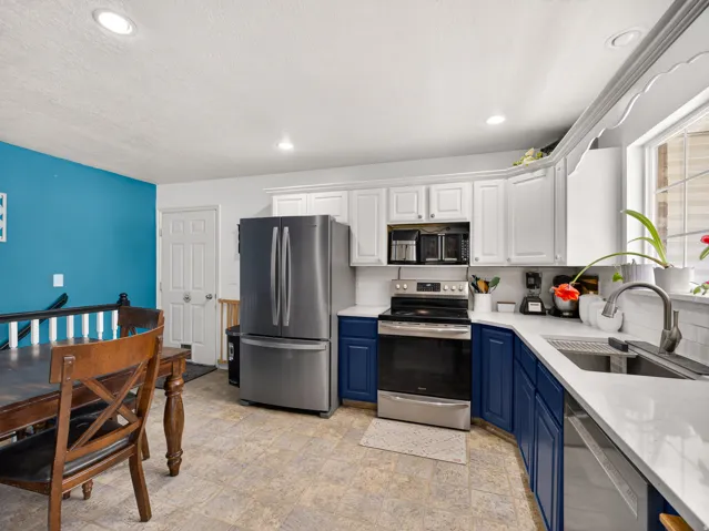 Modern kitchen featuring two-tone cabinetry, stainless steel appliances, recessed lighting, and light-toned countertops
