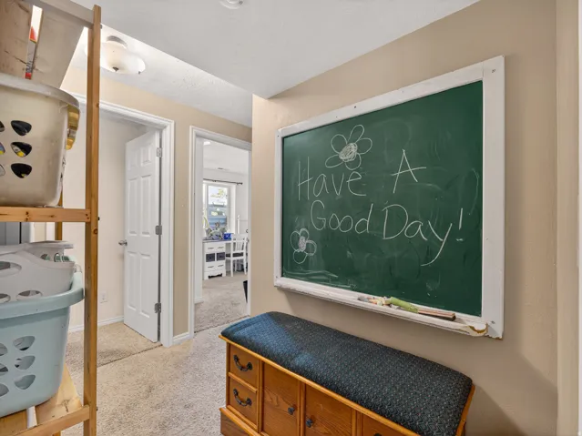 Basement hallway featuring a built-in chalkboard, neutral wall paint, and carpet flooring