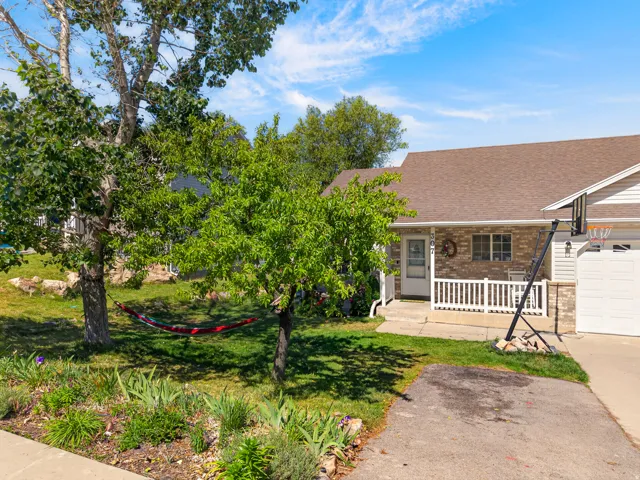 Brick facade home featuring a covered front porch with white railing, attached garage with white door, and a brown shingle roof