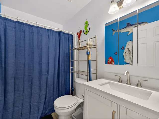 Main floor bathroom featuring a white vanity with integrated sink, brushed nickel faucet, and a wall-mounted mirrored medicine cabinet