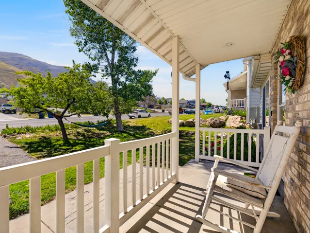 Inviting covered front porch with white railings and a brick exterior