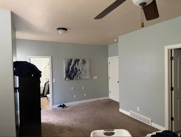 Spacious room featuring carpeted flooring, light blue wall paint, white trim, and white interior doors with dark hardware