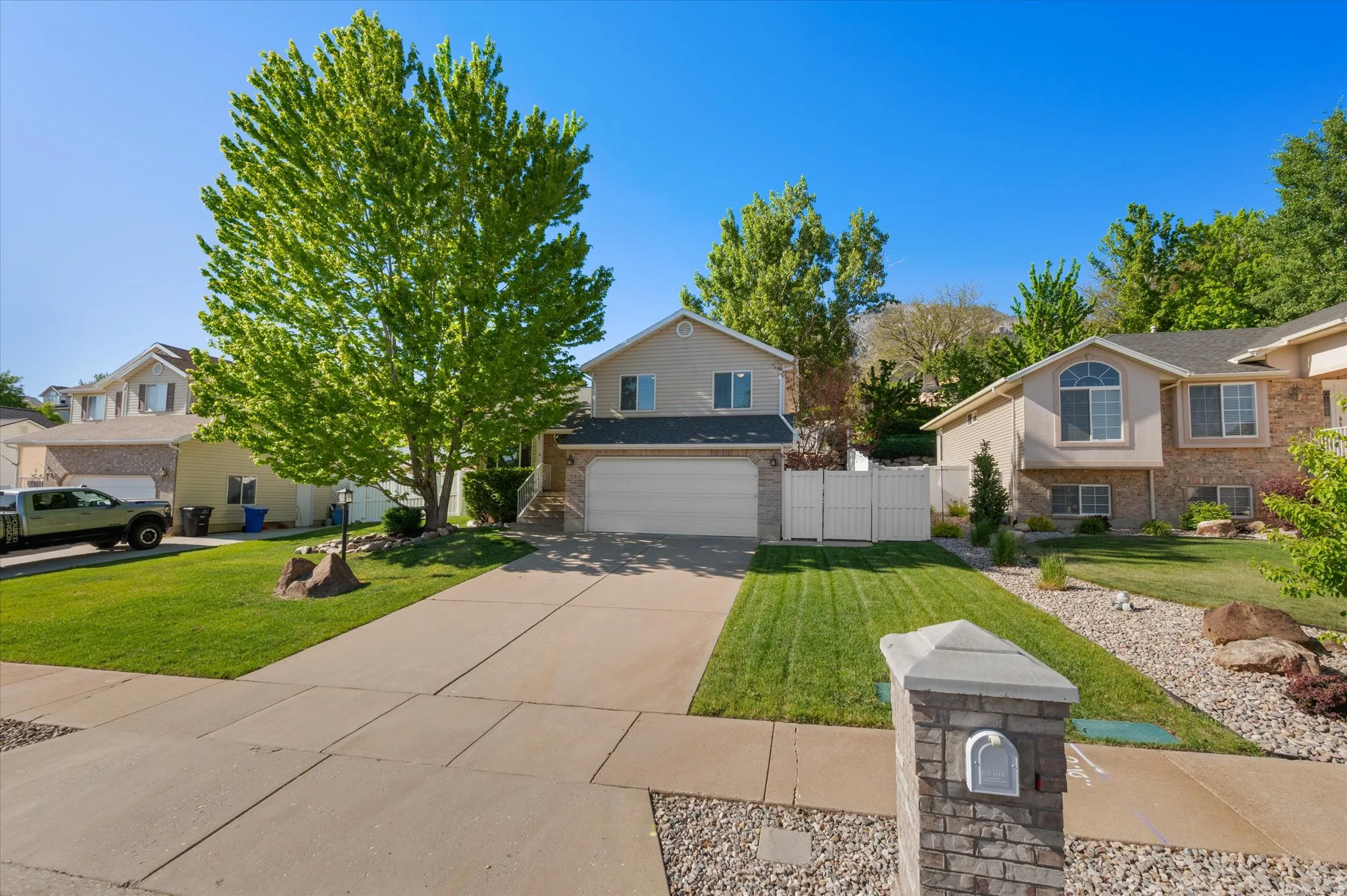 Tri-multi level  residence featuring a two-car garage, mature landscaping, and an extended concrete driveway