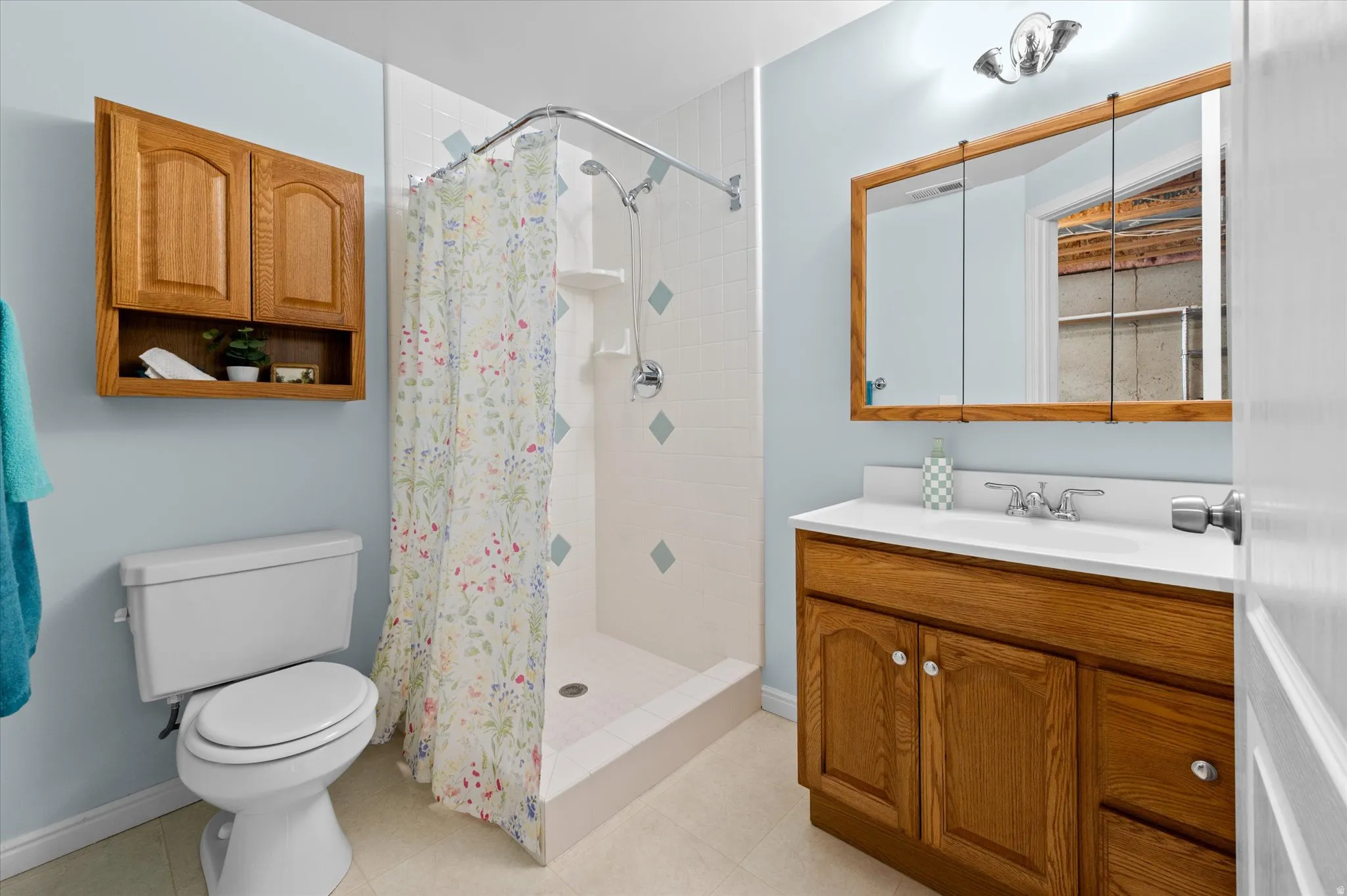 Bathroom with a single vanity, white countertop, chrome faucet, and wood-finish cabinetry