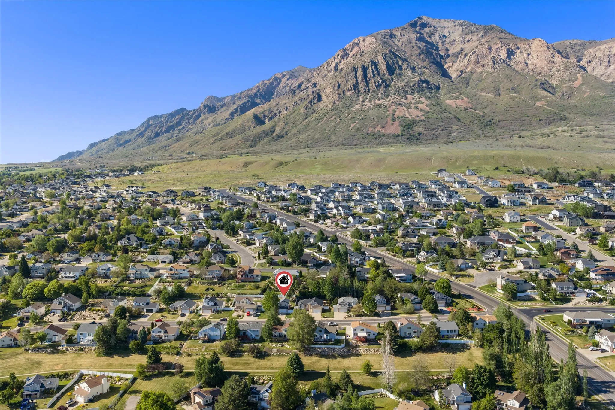 Aerial perspective of a residential community with abundant mature trees and mountainous terrain