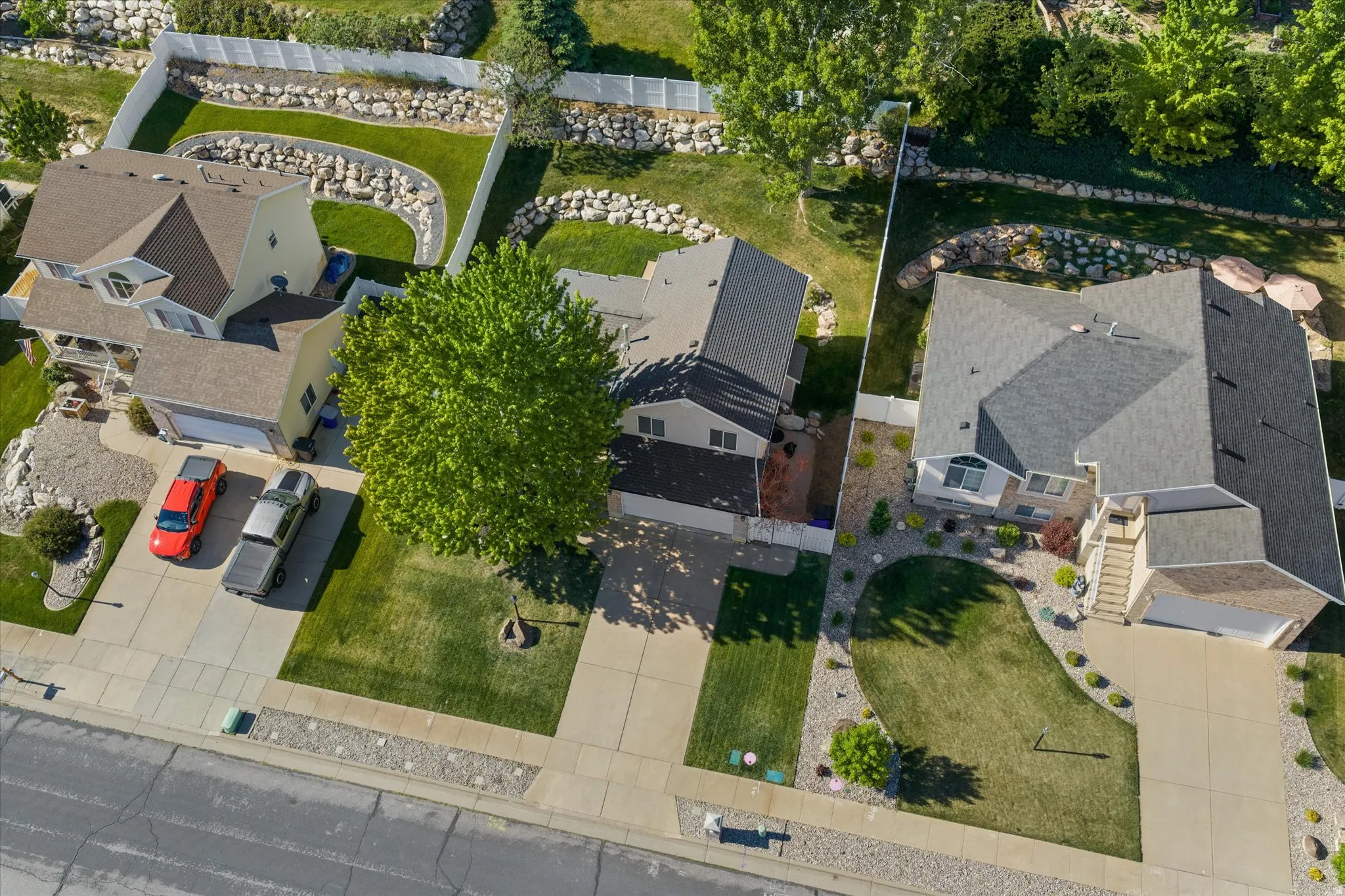 Aerial view of three single-family homes with pitched shingle roofs and integrated garages