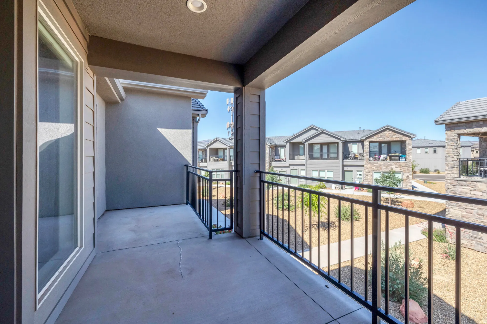 Covered outdoor patio with concrete flooring, recessed lighting, and black metal railings