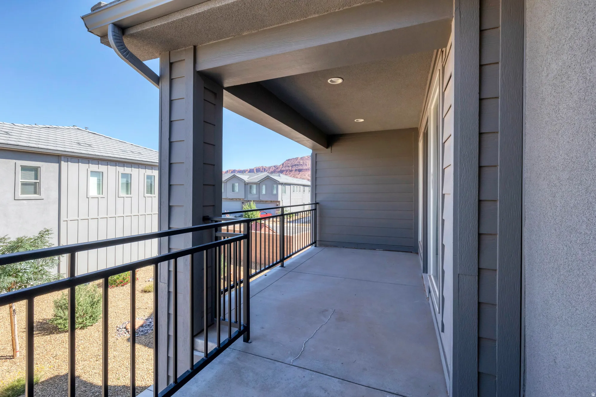 Covered balcony featuring concrete flooring, black metal railings, and recessed lighting