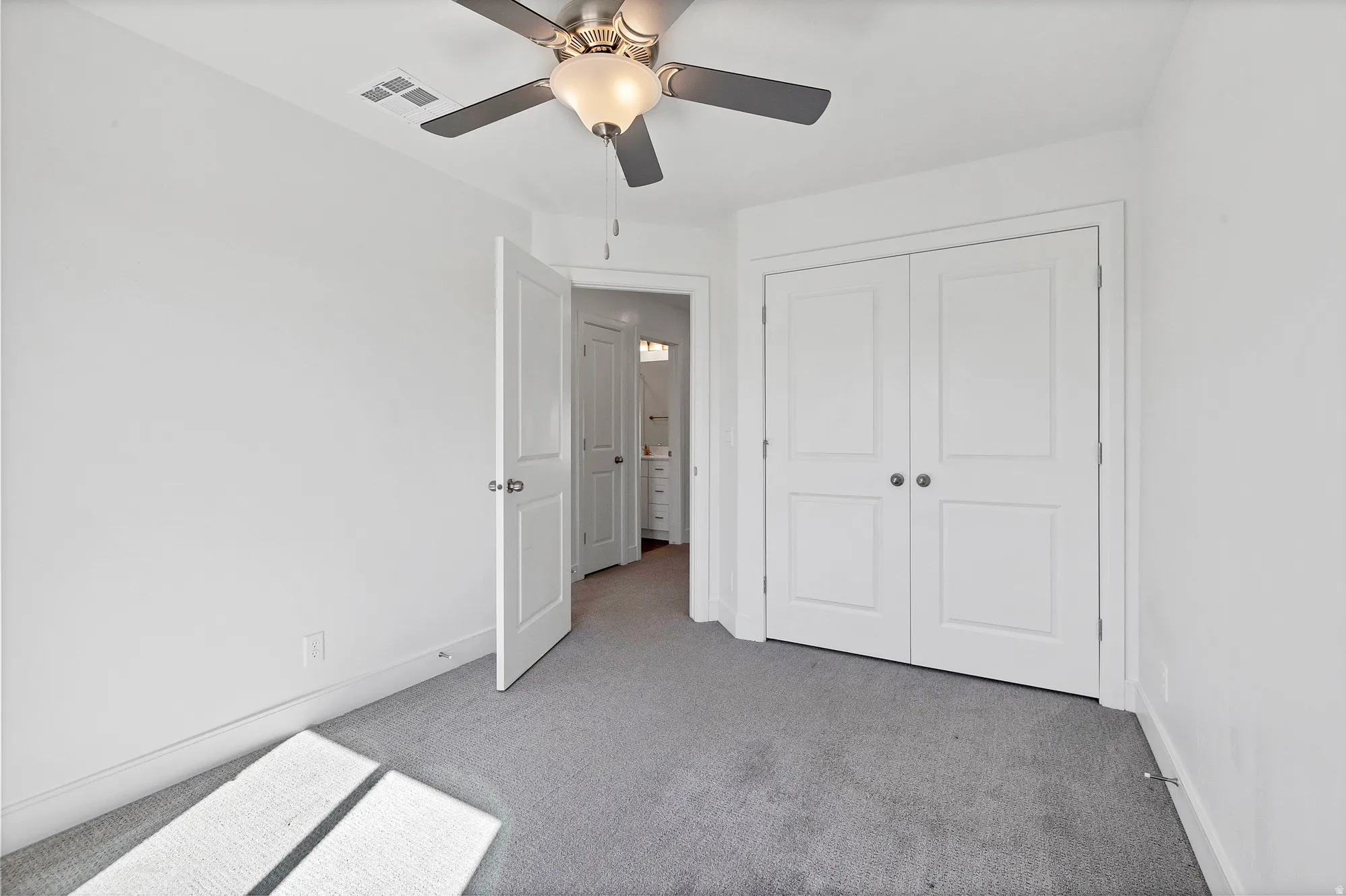 Neutral tone carpeting complementing white walls, with a ceiling fan overhead