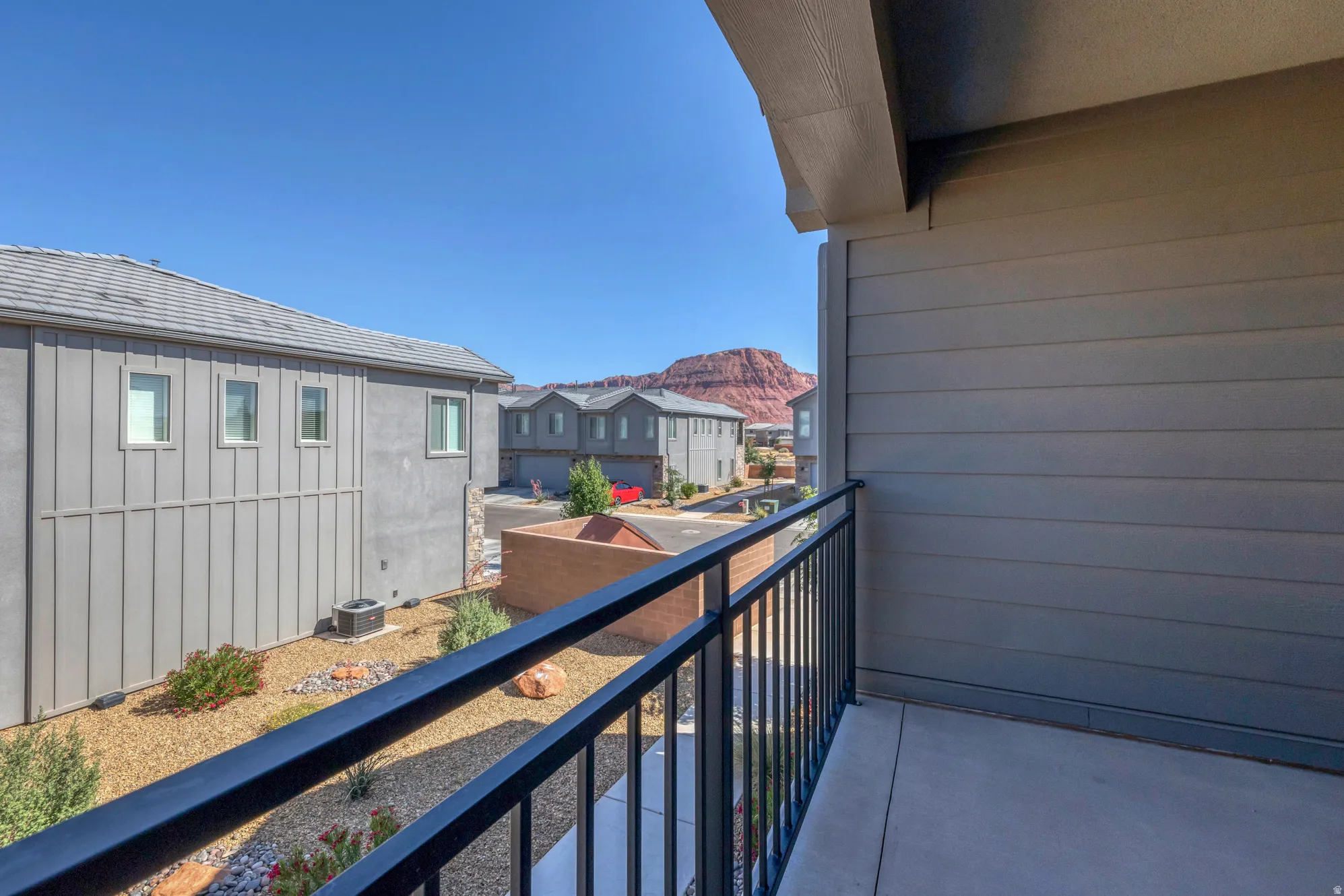 Private outdoor balcony with concrete flooring and dark metal railings