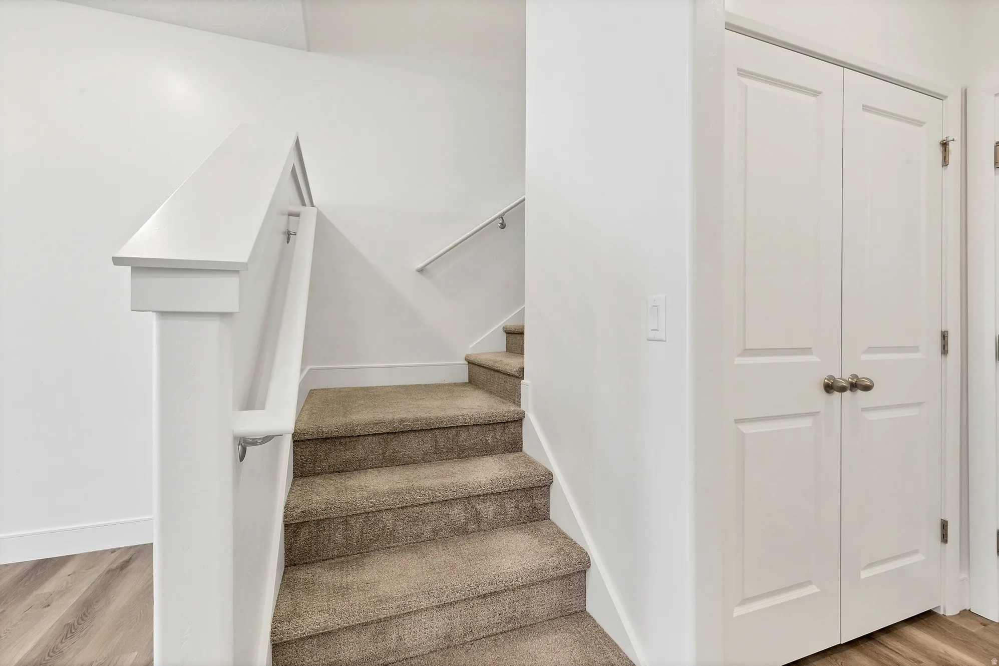 Carpeted staircase with white balusters and handrails