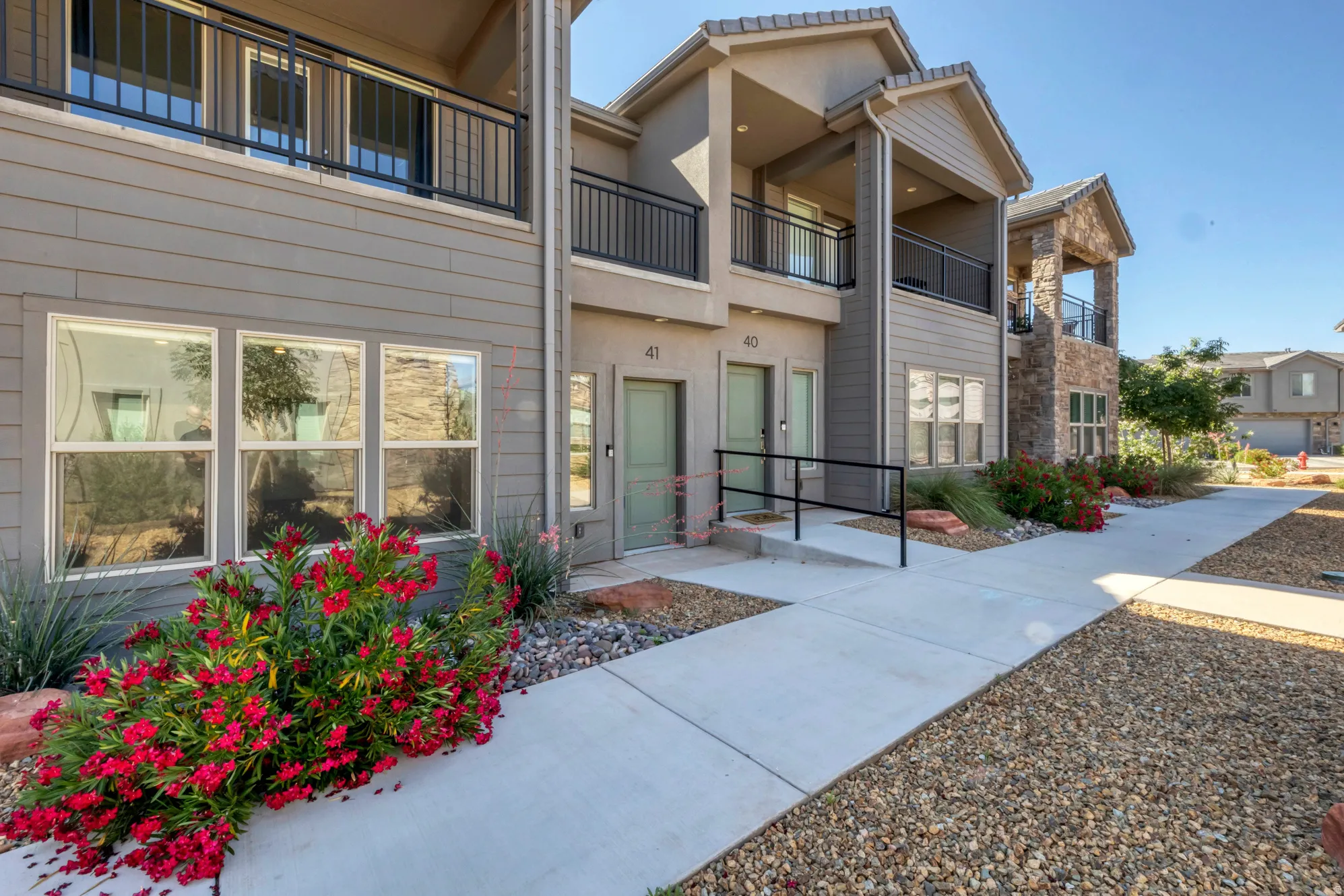 Contemporary multi-story exterior with horizontal siding, stone accents, and covered balconies featuring black railings