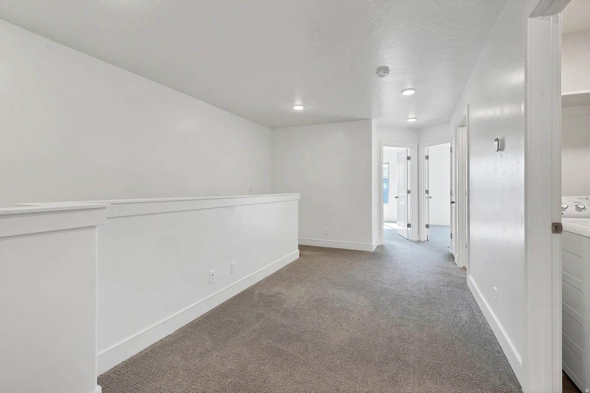 Carpeted loft area featuring white walls, recessed lighting, and white baseboards