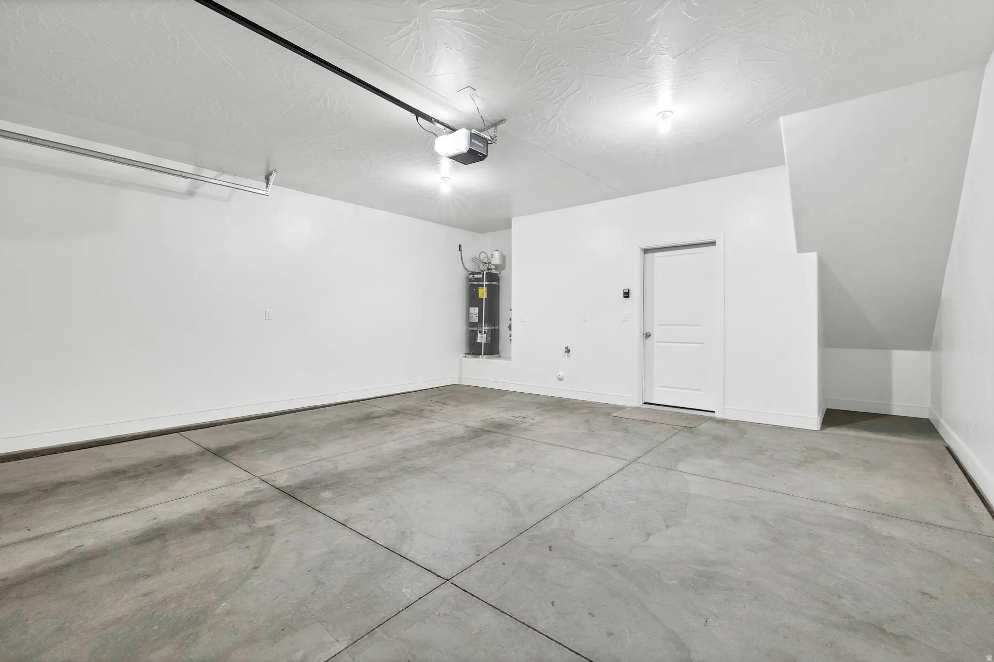 Spacious garage featuring a concrete floor, painted walls, and an overhead garage door opener
