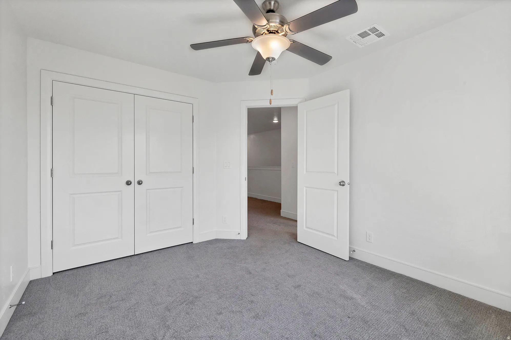 Spacious room featuring plush gray carpeting and white walls