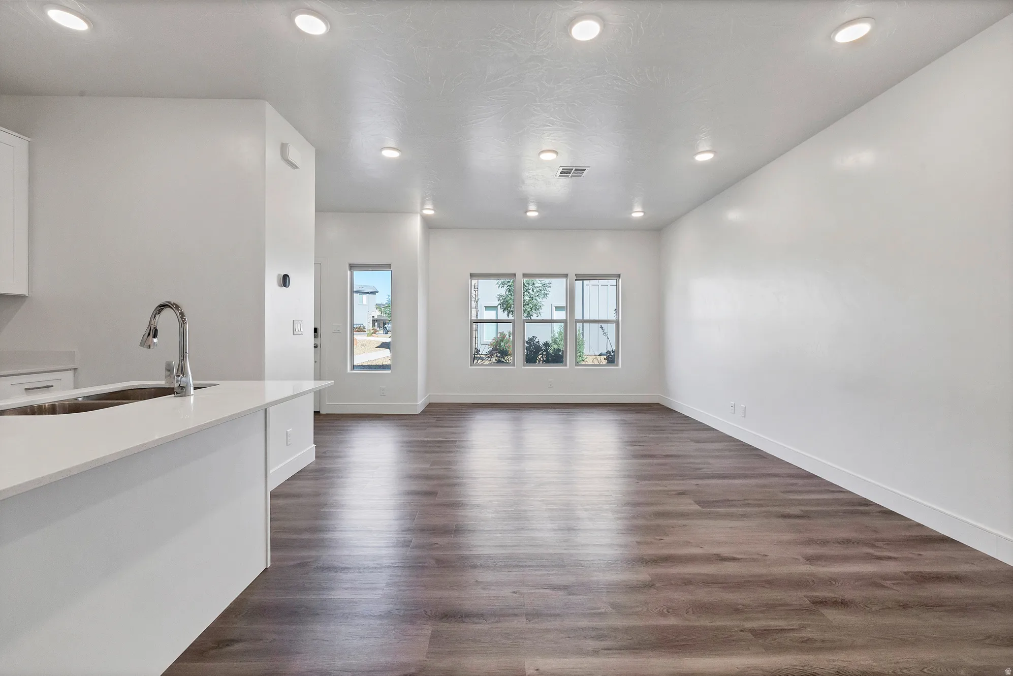 Open-concept living area with wood-finish flooring, recessed lighting, and multiple windows