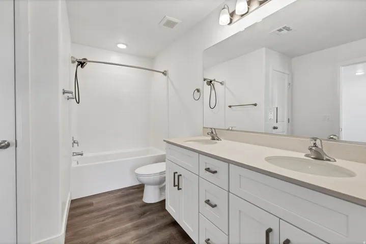 Bathroom featuring a dual-sink vanity with light-toned countertops, white cabinetry, and brushed nickel hardware