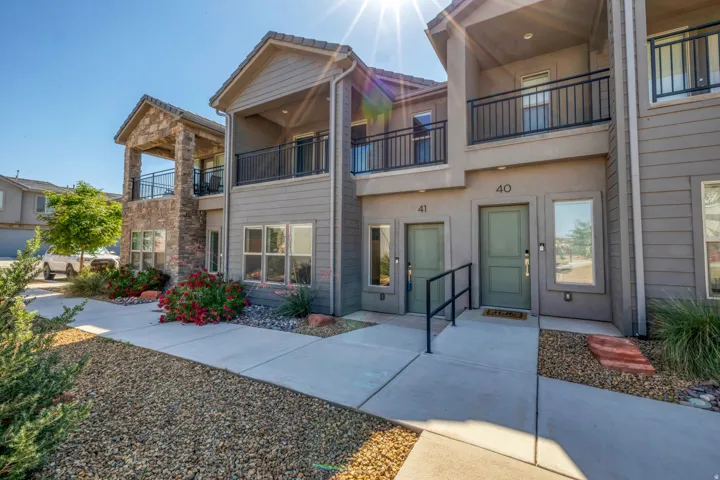 Contemporary facade featuring stone accents, multiple balconies with black railings, and a gravel and concrete entryway