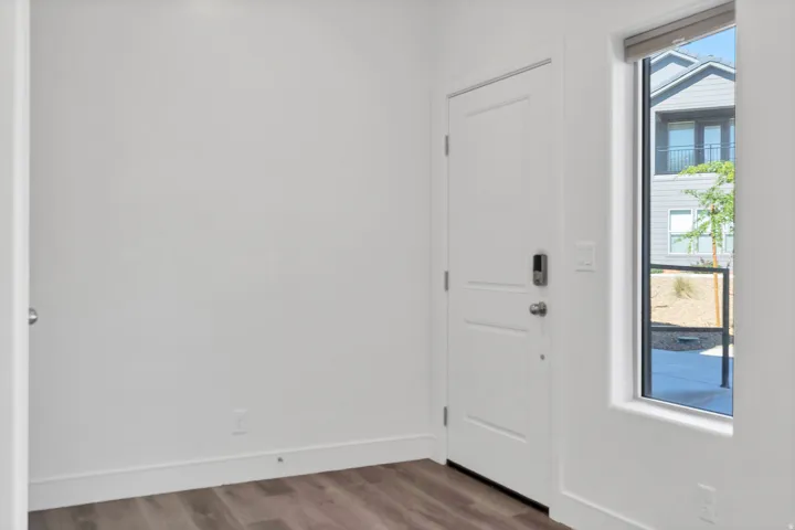 Entryway featuring wood-finish flooring and a contemporary white door with smart lock