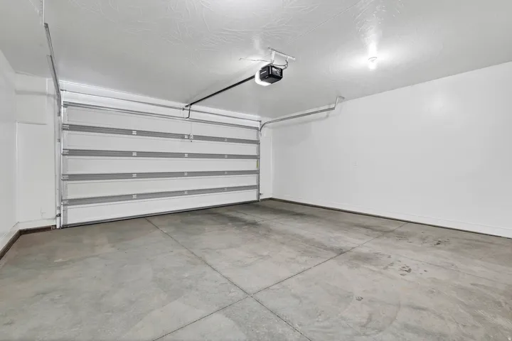 Spacious garage featuring a sectional overhead door with automatic opener, concrete flooring, and overhead lighting