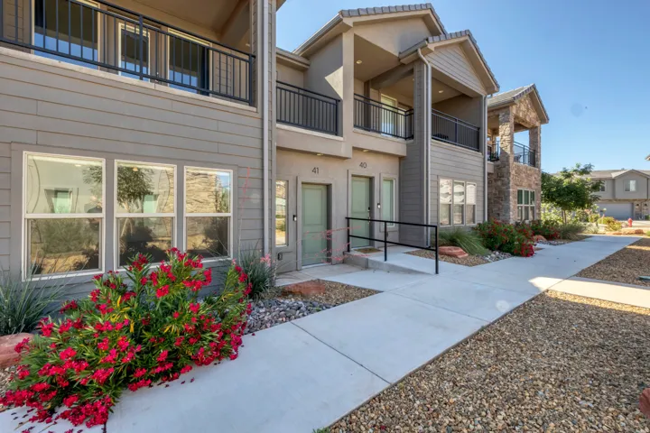 Contemporary multi-story exterior with horizontal siding, stone accents, and covered balconies featuring black railings
