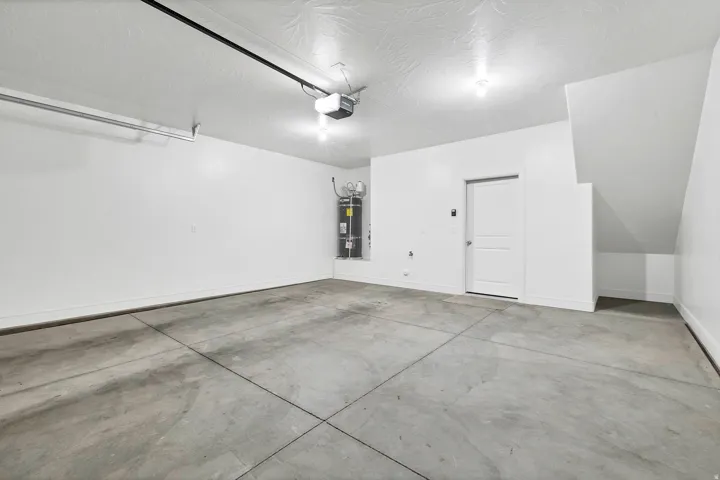 Spacious garage featuring a concrete floor, painted walls, and an overhead garage door opener