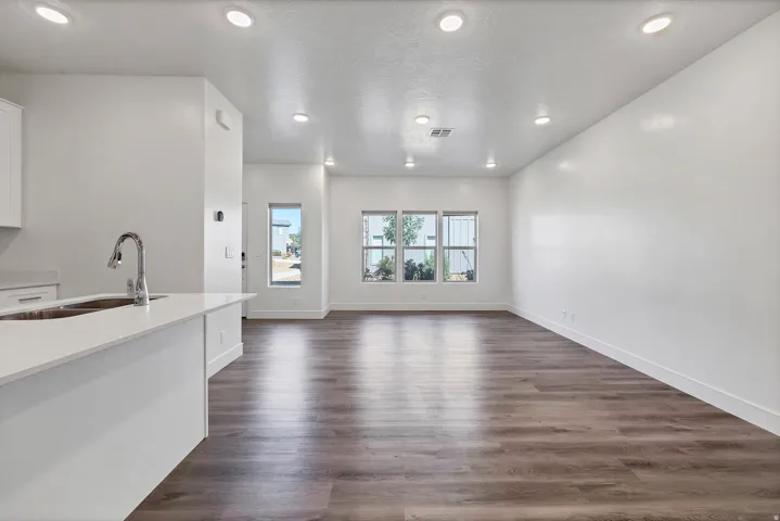 Open-concept living area with wood-finish flooring, recessed lighting, and multiple windows