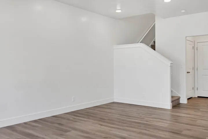 Living area featuring contemporary wood-finish flooring, recessed lighting, and a staircase with white balustrade and carpeted treads