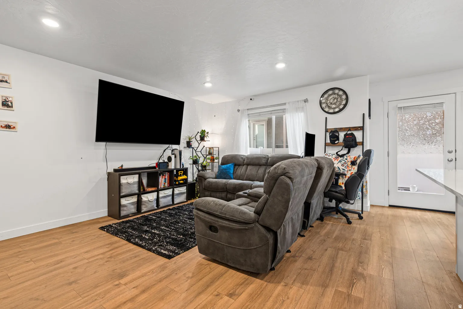 Spacious living area featuring wood-finish flooring, recessed lighting, and white walls