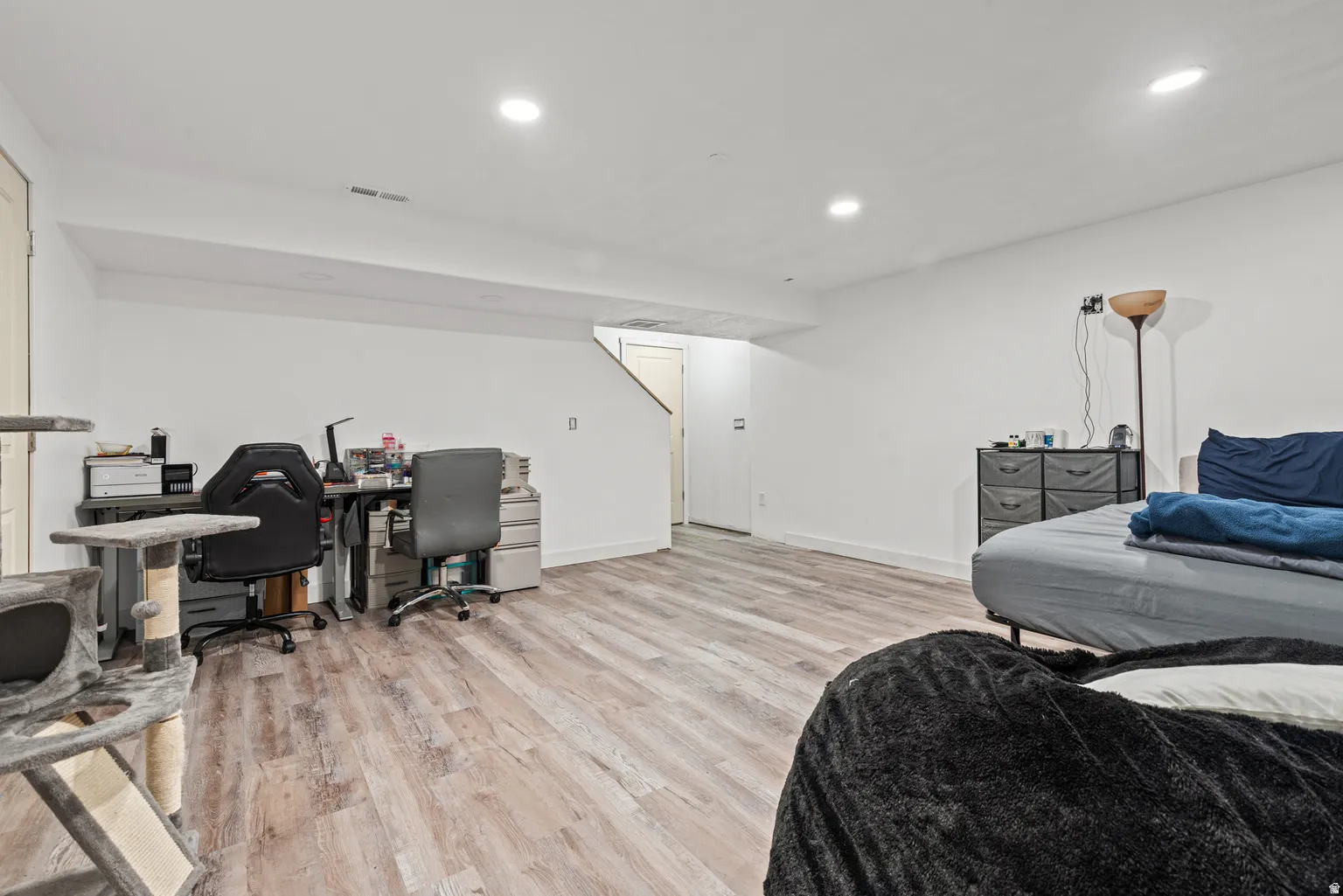 Spacious room featuring wood-finish flooring, recessed lighting, and white painted walls