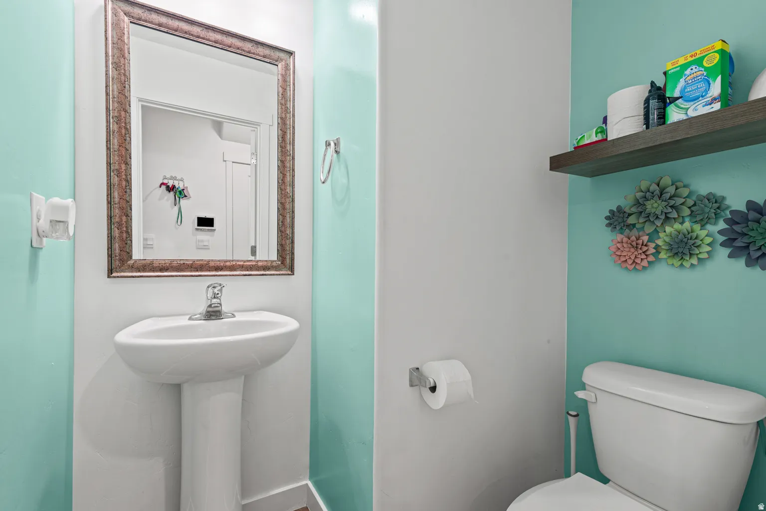 Pedestal sink with a framed mirror and chrome faucet