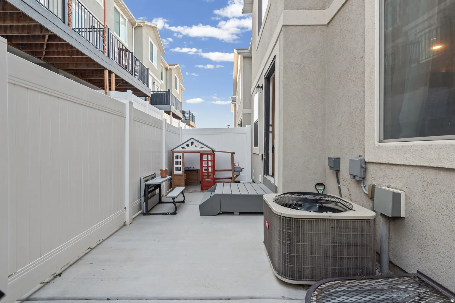 Private patio area featuring a concrete surface and a tall white privacy fence