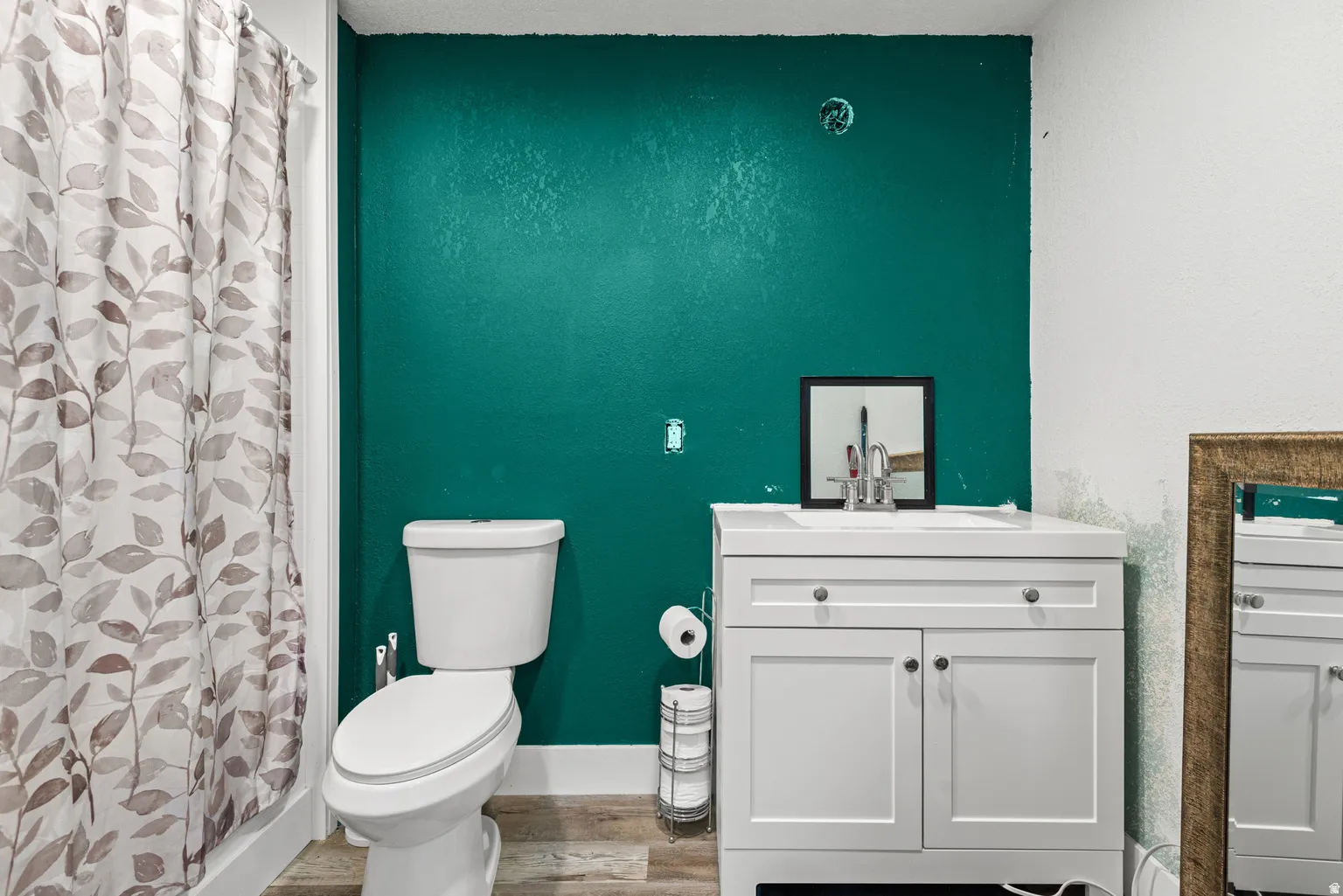 Bathroom featuring a white vanity with panel cabinetry and a contrasting teal accent wall