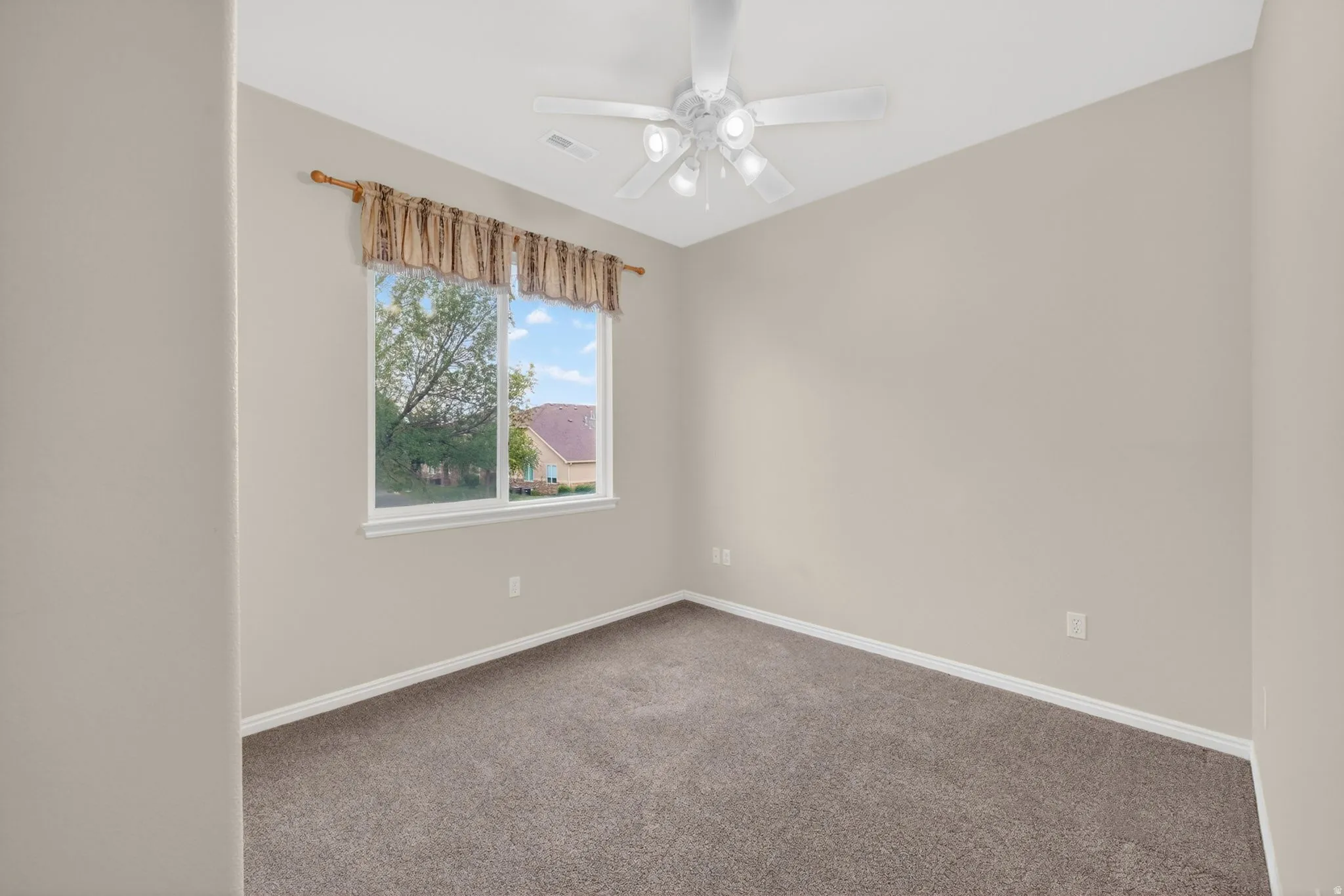 Neutral tone wall paint with white trim, brown carpet flooring, and a ceiling fan with integrated lighting