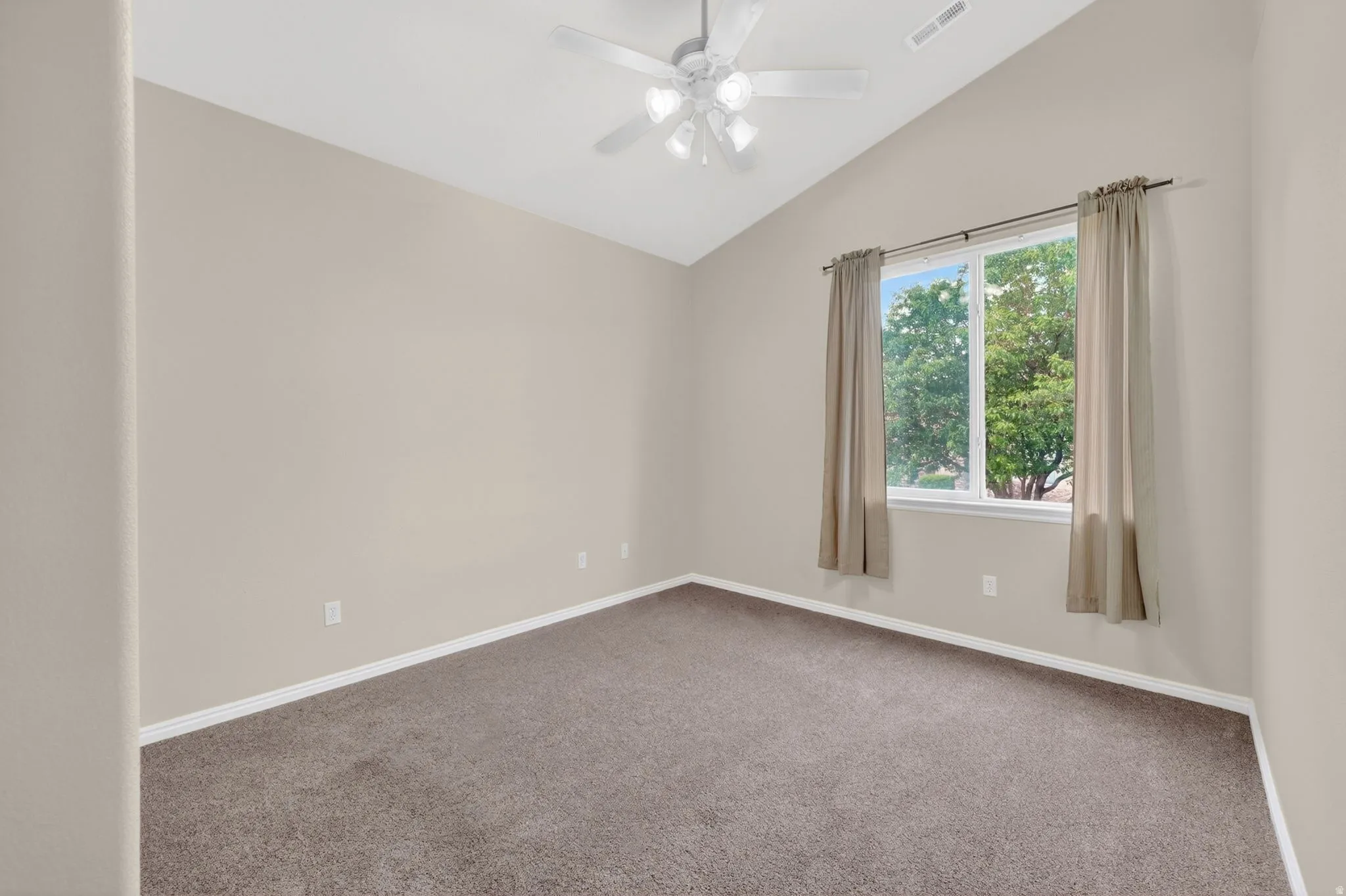 Vaulted ceiling room featuring carpet flooring, a ceiling fan with integrated lighting, and a double window