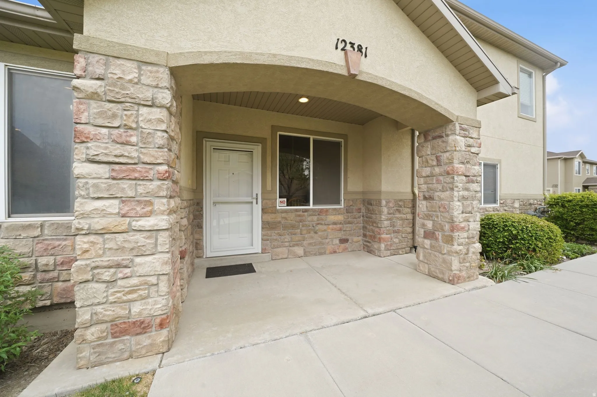 Stone veneer and stucco exterior with an arched entry