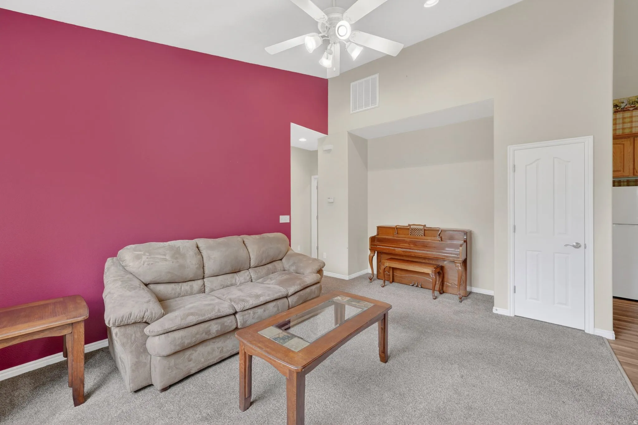 Vaulted ceiling living area featuring a ceiling fan, recessed lighting, and a brightly colored accent wall