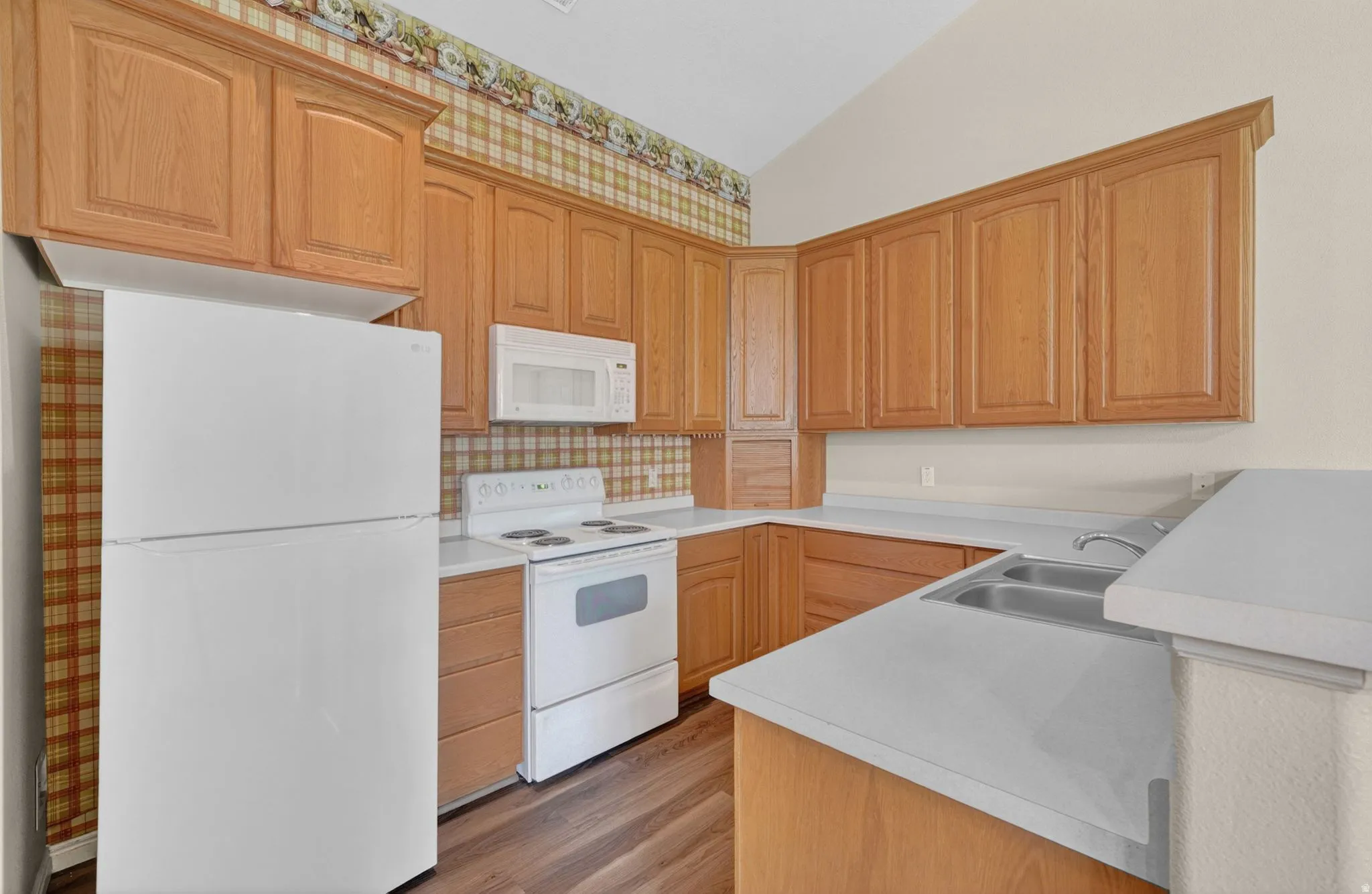 Kitchen featuring wood-finish cabinetry, solid surface countertops, and a double basin sink