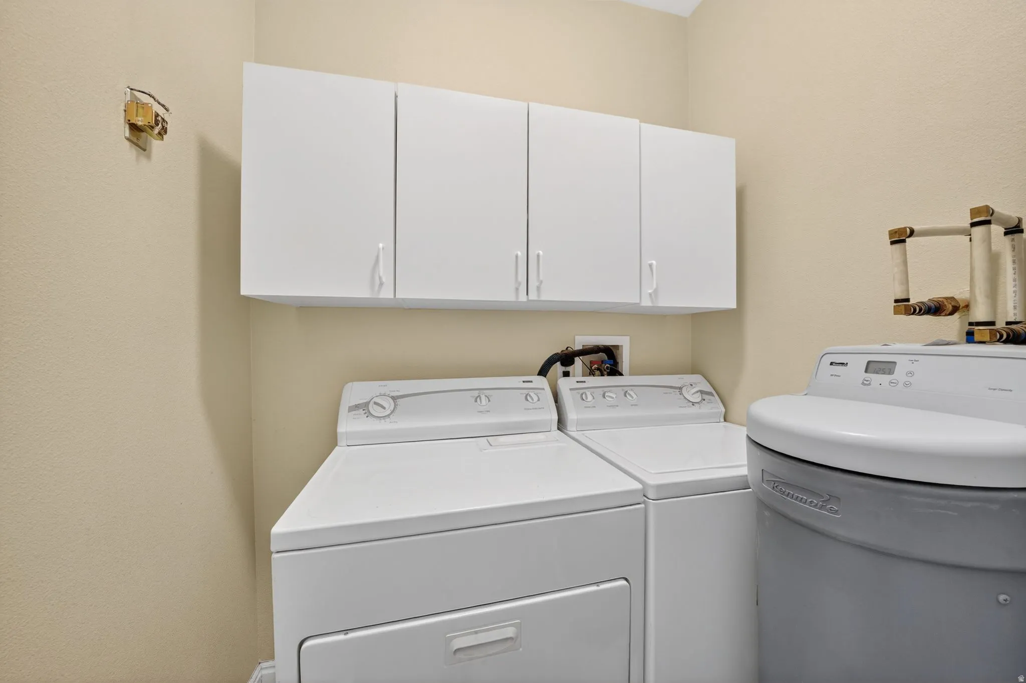 Dedicated laundry area featuring overhead white cabinetry for storage