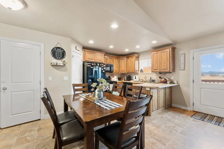 Open-concept kitchen and dining area featuring warm wood cabinetry, neutral countertops, and a full suite of black appliances