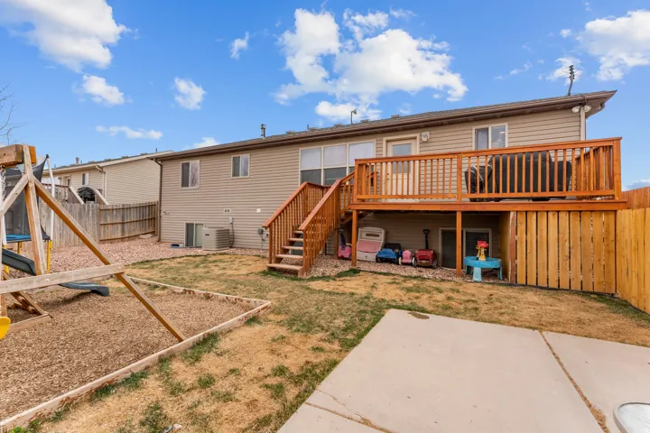 Expansive backyard featuring a wood deck with stairs, a concrete patio, and a wood fence enclosing the perimeter