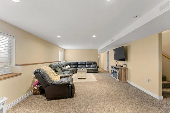 Spacious lower-level living area featuring neutral-toned carpeting, recessed lighting, and a built-in entertainment console